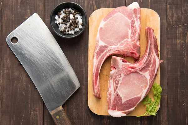 Carne fresca cruda en tabla de cortar y cuchilla sobre fondo de madera — Foto de Stock