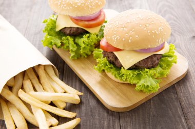 Çizburger ahşap masa üzerinde patates kızartması ile