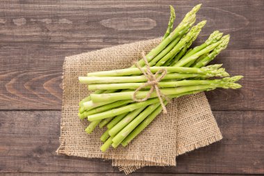 Rustik ahşap bir masa üzerinde taze yeşil kuşkonmaz demet