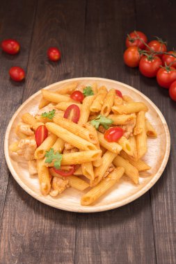 Ahşap bir masa üzerinde tavuk domates soslu Penne makarna