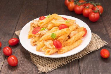 Ahşap bir masa üzerinde tavuk domates soslu Penne makarna