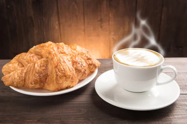 Ontbijt koffiekopje en croissants op houten tafel — Stockfoto