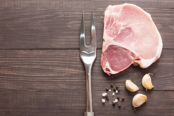 Raw roast meat and meat fork on wooden background — Stock Photo, Image