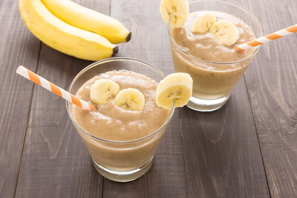 Banana smoothie i świeżych bananów na drewnianym stole — Zdjęcie stockowe