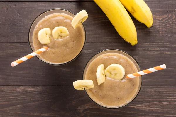 Banana smoothie i świeżych bananów na drewniane tła — Zdjęcie stockowe