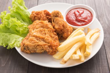 Kızarmış tavuk ve patates kızartması ahşap arka plan üzerinde