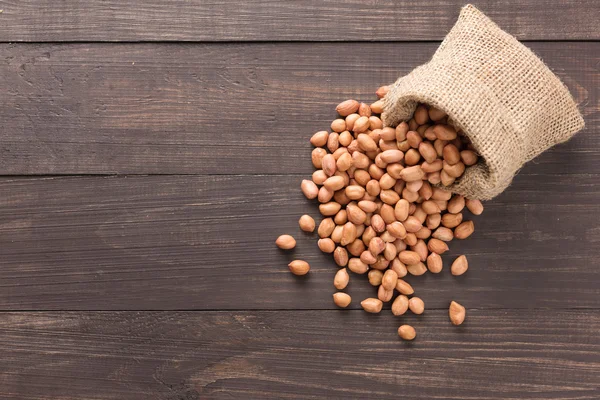 Peanut in sacks on the wooden background — Stock Photo, Image