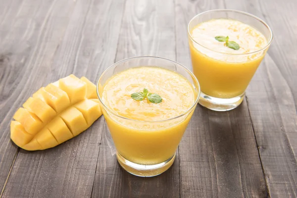 Mango smoothie and yellow mango on wooden table — Stock Photo, Image