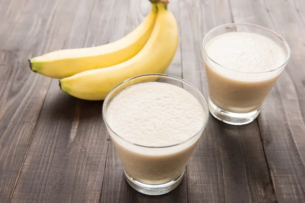 Banana smoothie i świeżych bananów na drewnianym stole — Zdjęcie stockowe