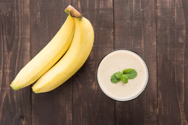 Banana smoothie and fresh banana on wooden table — Stock Photo, Image