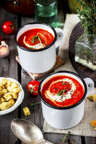 Tomato cream soup in mugs and greens on a wooden table. — Stock Photo, Image