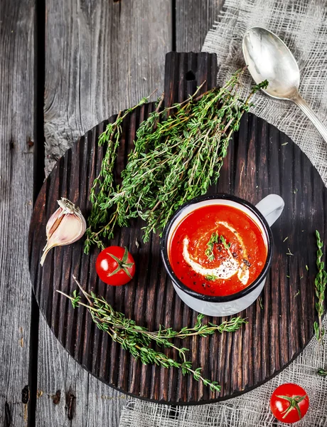 Суп из томатных сливок в кружке и тимьян на деревянном столе . — стоковое фото
