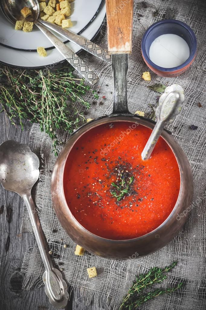 Tomato cream soup in vintage copper ladle on a wooden table. — Stock