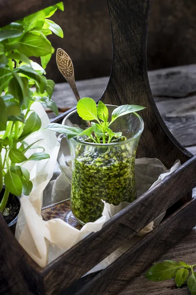 Molho de pesto de manjericão em vidro na mesa de madeira . — Fotografia de Stock