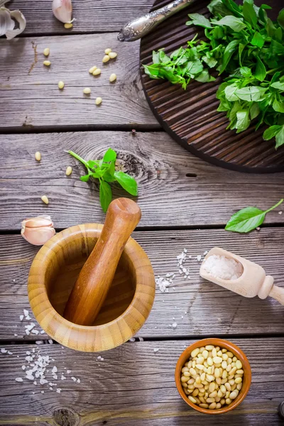Ingredientes para pesto e argamassa de madeira na mesa . — Fotografia de Stock