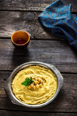 Ahşap masa üzerinde metal kapta humus.