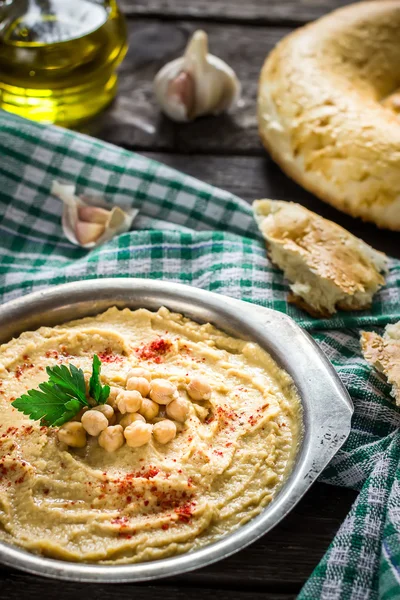 Hummus en cuenco de metal sobre mesa de madera . — Foto de Stock