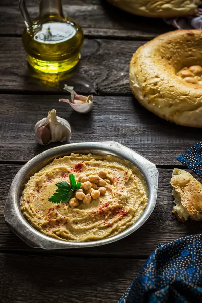 Hummus en cuenco de metal sobre mesa de madera . — Foto de Stock