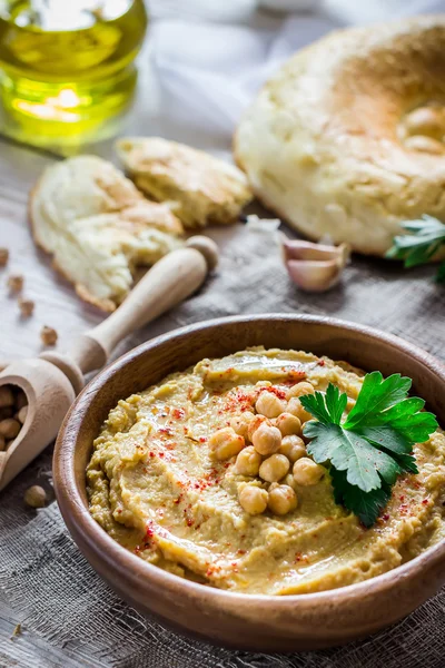 Hummus en cuenco de madera sobre la mesa . — Foto de Stock