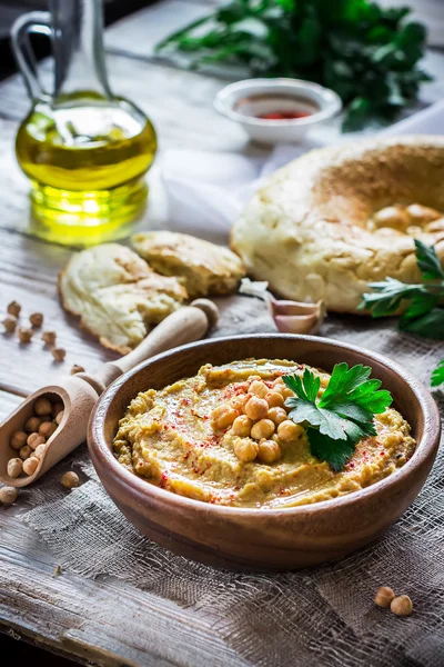 Hummus en cuenco de madera sobre la mesa . — Foto de Stock