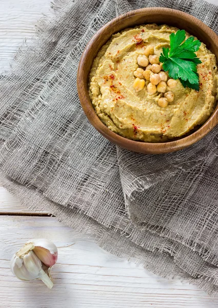 Hummus in ciotola di legno sul tavolo . — Foto Stock