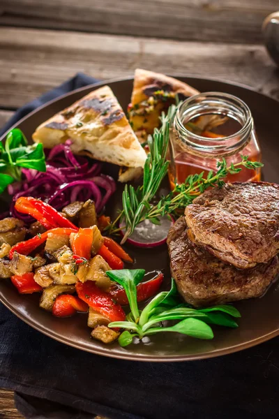 Жареное мясо с овощами и соусом на тарелке . — стоковое фото