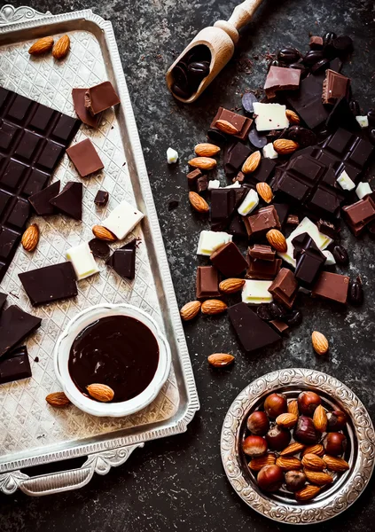 Different varieties of chocolate on metal tray and nuts — Stock Photo, Image