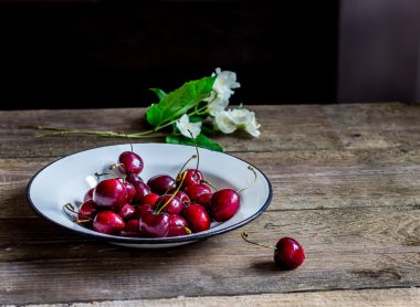 Tatlı kiraz ahşap masa üzerinde beyaz kase. 