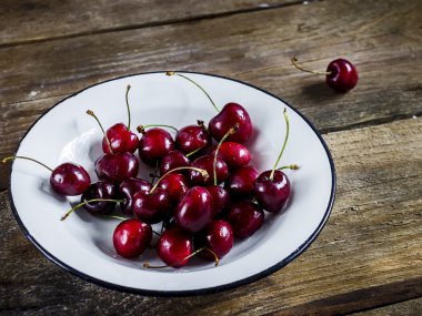 Tatlı kiraz ahşap masa üzerinde beyaz kase.