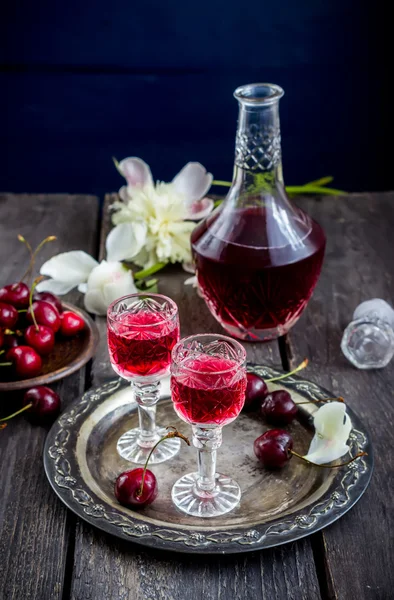 Metal tepsi üzerinde gözlük, kiraz ve vintage şişede kiraz likörü.