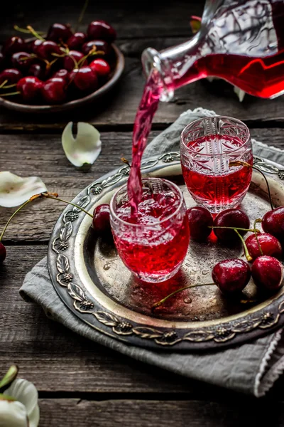 Licor caseiro de cereja fluindo em um copo vintage . — Fotografia de Stock
