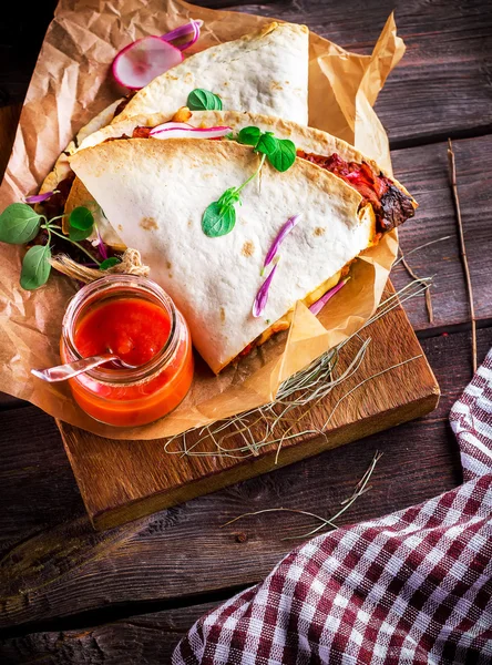 Flat cake with meat and vegetables and sauce in glass on cutting board — Stock Photo, Image