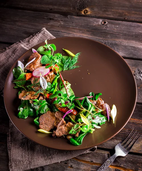 Salada com carne, verduras e rabanete de jardim em prato marrom . — Fotografia de Stock