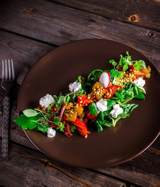 Salada com queijo de cabra, verduras e pimenta grelhada em prato marrom . — Fotografia de Stock