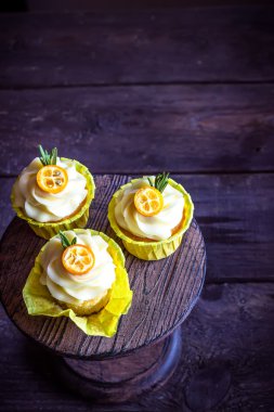 Mandalina koyu ahşap masa üzerinde süslenmiş cupcakes.