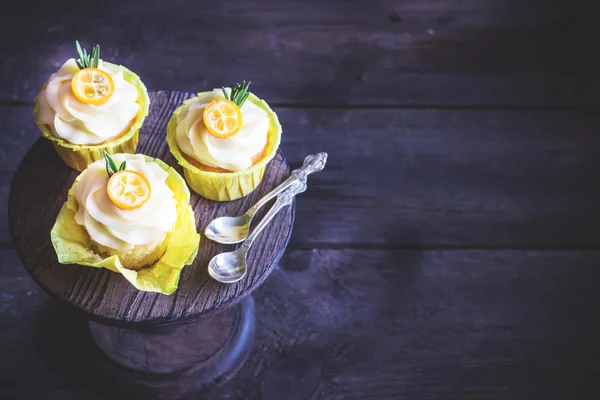 Cupcakes decorated with cumquat on dark wooden table. — Stock Photo, Image