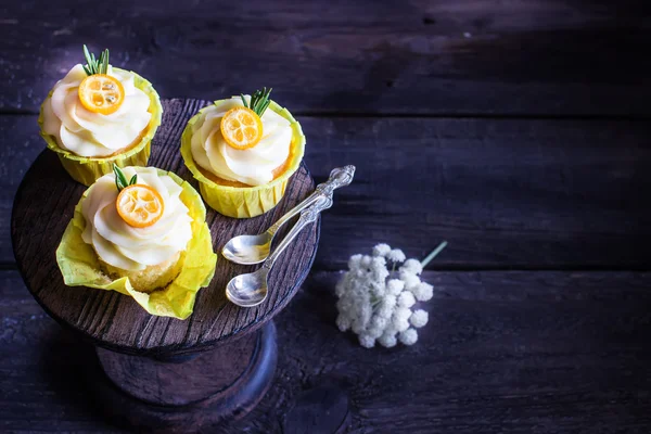 Gâteaux décorés de cumquat sur une table en bois sombre . — Photo