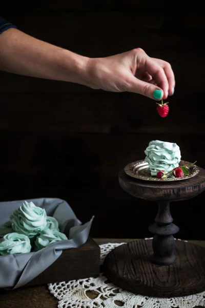 Meringue dessert on support decorating with raspberry on wooden table. — Stock Photo, Image