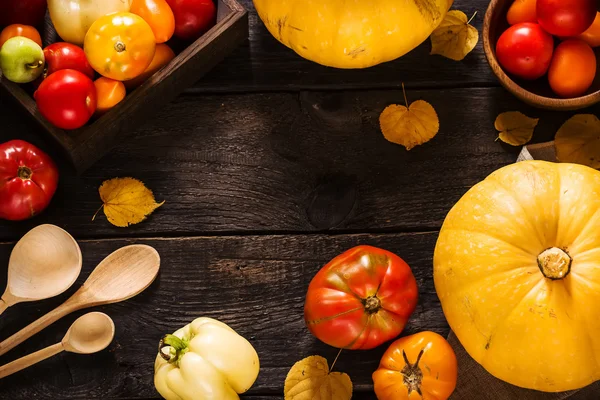 Herfst natuur concept. Pompoenen en tomaten op donkere houten tafel. — Stockfoto