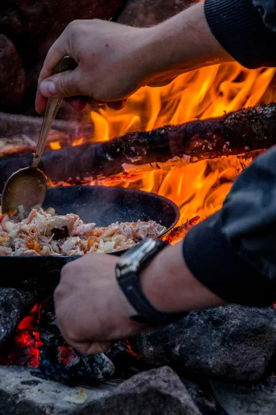 El hombre cocinando comida en un fuego . — Foto de Stock