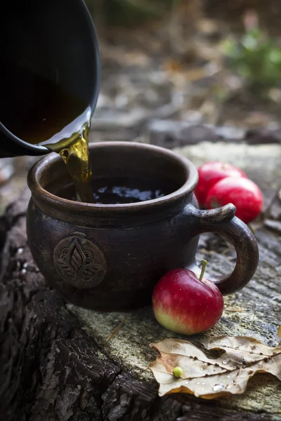 Hälla varmt te i koppen och röda äpplen på påbörjad. — Stockfoto