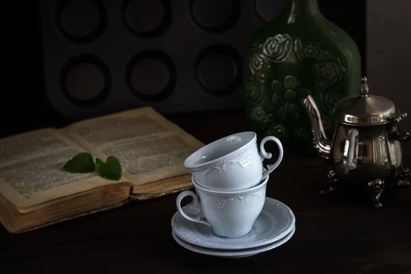 Натюрморт с чашками и книга в винтажном стиле — стоковое фото