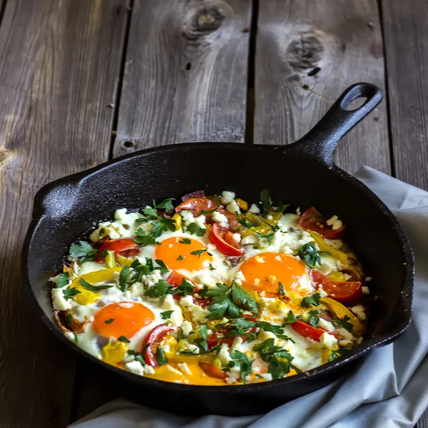 Huevos escalfados con verduras, llamados "shakshouka" en la mesa de madera. Estilo rústico . — Foto de Stock