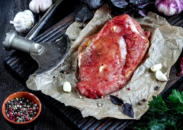 Carne cruda con ajo y hierbas y hacha sobre mesa de madera. Estilo rústico. Enfoque selectivo . — Foto de Stock