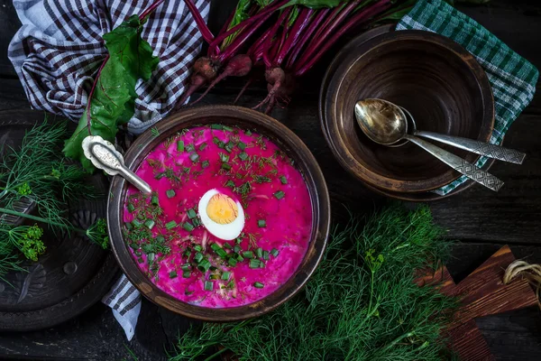 Sopa fría rusa con remolacha, tazón, cucharas, vegetación en la mesa de madera oscura. Estilo rústico . — Foto de Stock