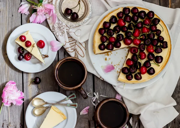 Cheesecake with cherry, two slices on saucers and metal tray  on a wooden table. . — Stock Photo, Image