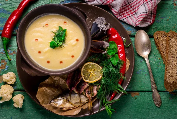 Sopa de crema de coliflor en tazón de cerámica sobre mesa de madera verde . — Foto de Stock