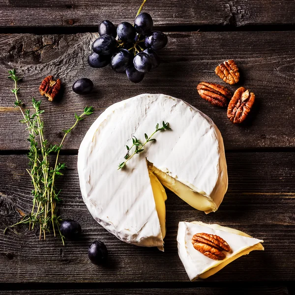 Queso, hierbas, nueces y uva en mesa de madera oscura. Vista aérea . — Foto de Stock