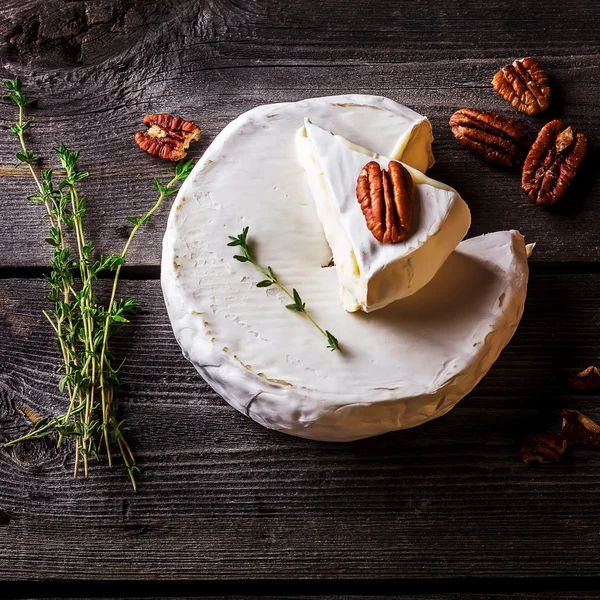 Queso, hierbas y frutos secos sobre mesa de madera oscura . —  Fotos de Stock