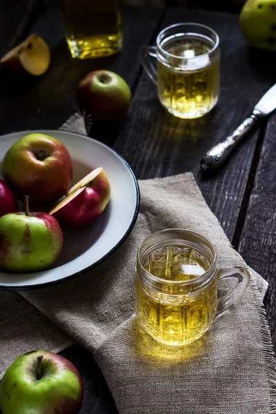 Jablečný mošt a jablka na starý plechový tác. Tmavý dřevěný stůl. — Stock fotografie
